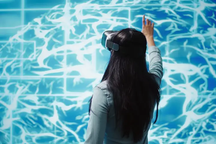 Kobieta w goglach VR dotyka wirtualnego mózgu, szukając sposobów na poprawę samopoczucia psychicznego.