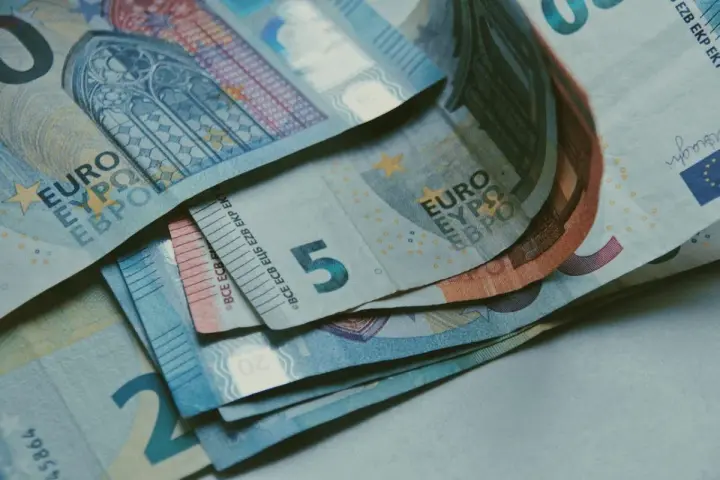 Euro banknoty, w tym 5, 20 i 50 euro, leżące na stole. Zastanawiasz się, jak rozliczyć się z ubezpieczenia w Holandii?