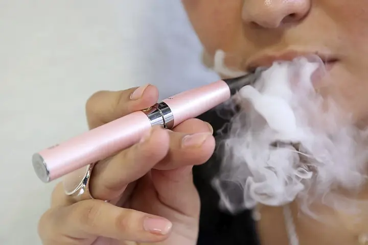 Persona usa un vapeador para dejar de fumar, exhalando una gran nube de vapor.
