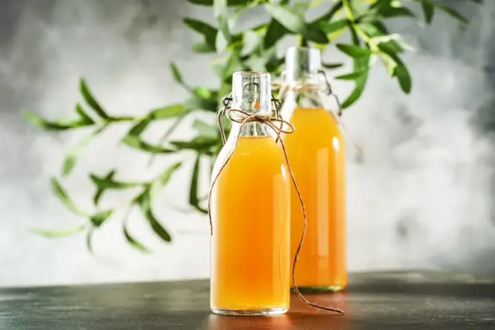 Dwie butelki z domową kombuchą, idealne do nauki jak zrobić grzyb kombucha.