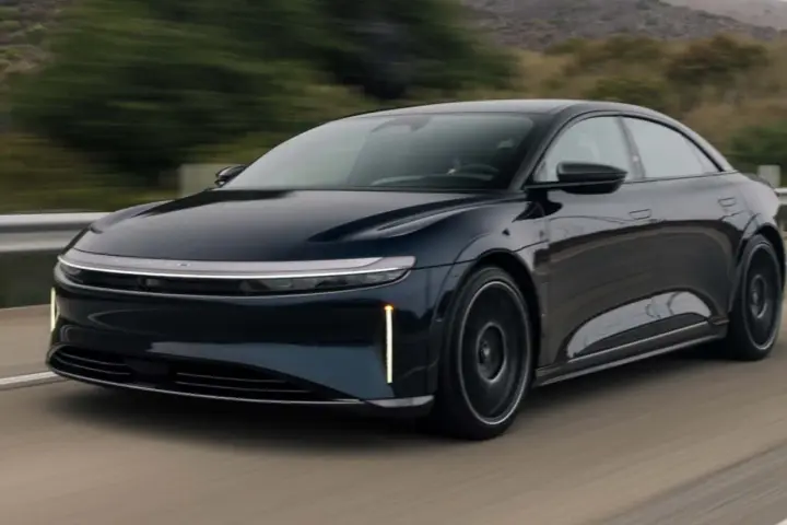 Ciemnoniebieski Lucid Air Sapphire pędzi po drodze, jego aerodynamiczna sylwetka i futurystyczne światła przyciągają wzrok.