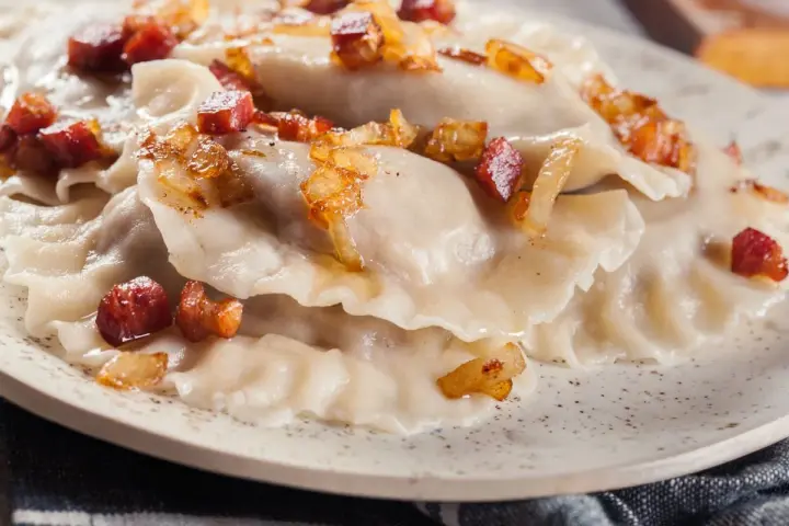 Pyszne dzyndzałki, czyli pierogi okraszone skwarkami i cebulką, kuszą na talerzu.