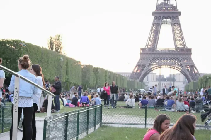 Gente disfrutando de un día soleado en París, con la Torre Eiffel de fondo. Un momento perfecto para la bise en France.