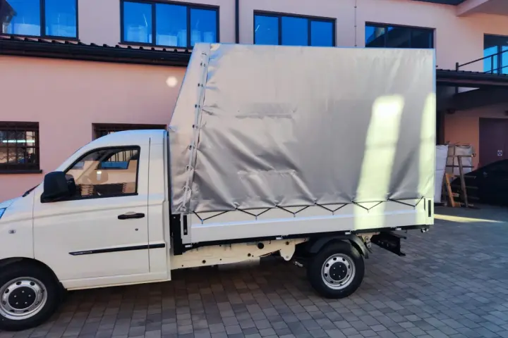 Biały samochód ciężarowy do 2,5 tony z plandeką gotowy do transportu towarów.