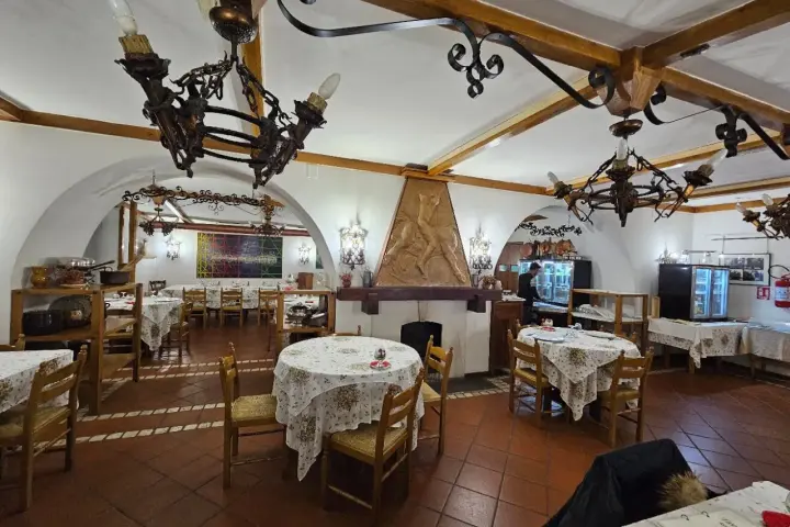Interno di un ristorante con tavoli apparecchiati e un camino decorato. Un'ottima opzione per sapere dove mangiare a Potenza.