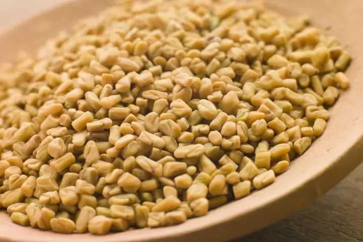 Graines de fenugrec sur une cuillère en bois, une aide naturelle pour gérer l'hypertension.
