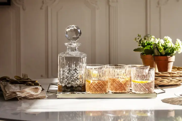 Elegancka karafka i szklanki z drinkami, idealne do degustacji whisky. Z czym pić whisky? Z cytryną i lodem, w dobrym towarzystwie.