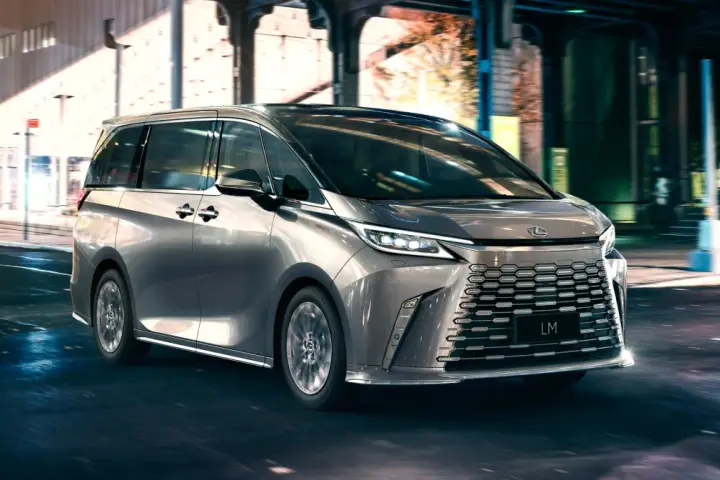 Srebrny van Lexus LM 350h na nocnej ulicy z rozmytym tłem.