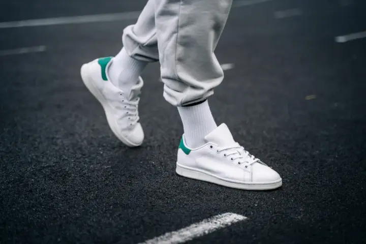 Un paio di sneakers bianche con dettagli verdi, simbolo di stile e comfort. Il loro significato va oltre la moda, rappresentando libertà di movimento.