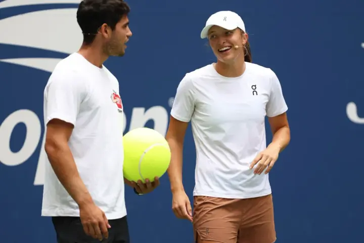 Carlos Alcaraz i Iga Świątek rozmawiają podczas Roland Garros 2024. Carlos trzyma wielką piłkę tenisową.