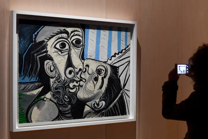 Un visitante captura con su móvil uno de los icónicos cuadros de Picasso, un beso en blanco y negro con toques de azul.