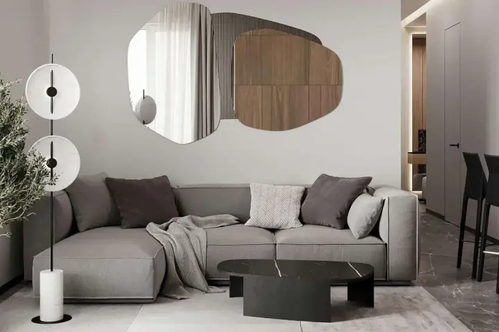 Nowoczesny salon z szarą sofą, geometrycznym lustrem i designerską lampą.