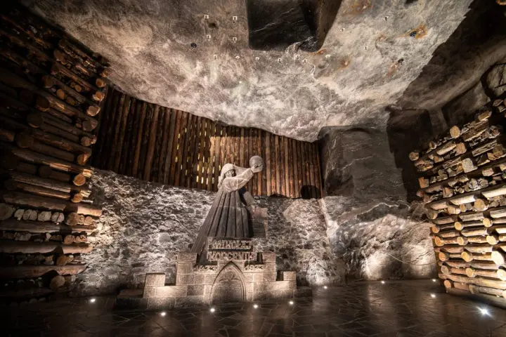 Kopalnia soli Wieliczka ciekawostki: rzeźba górnika Mikołaja Kopernika w solnej komorze, otoczona drewnianymi belkami i solnymi ścianami.