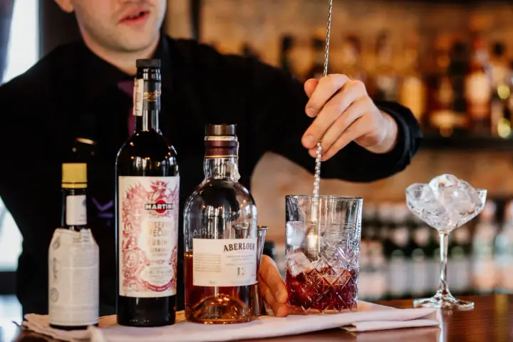 Barman miesza składniki na klasycznego Manhattan drinka. Obok butelki whisky Aberlour i Martini Riserva Speciale Rubino.