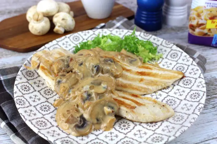 Sabroso pollo con champiñones en salsa cremosa, servido con lechuga fresca en un plato decorado.