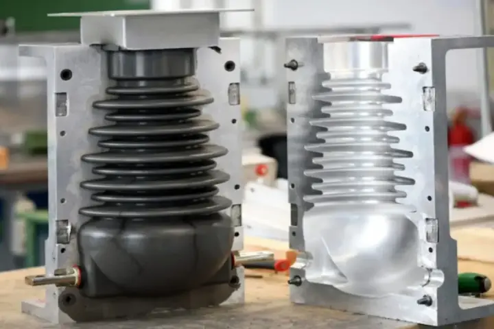 Two halves of a mold for compression molding products, one showing a black bellows-like component, the other an empty cavity.