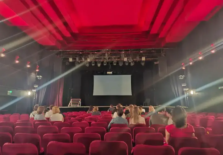 Widownia w Teatrze Palladium w Warszawie. Czerwone fotele i scena z ekranem czekają na widzów.