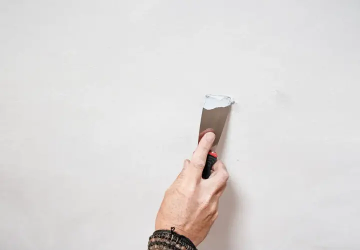 Mano che stende stucco su una parete per la pittura soffitto.