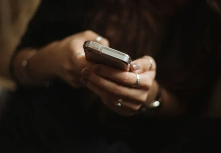Dłonie z pierścionkami trzymają telefon. Zastanawiasz się paypo co to? To wygodny sposób na płatności online.