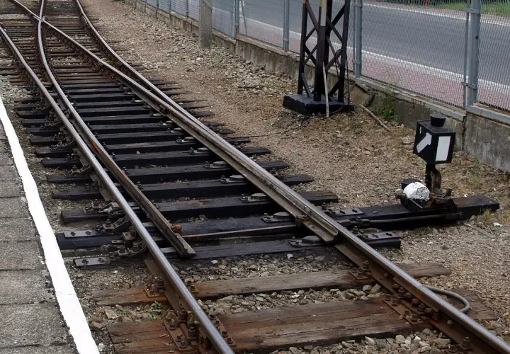 Zwrotnica kolejowa z nastawczym suwakowym mechanizmem. Minimalna droga oporowa klamry w zamknięciu nastawczym suwakowym jest kluczowa dla bezpieczeństwa.