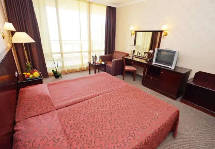 Pokój hotelowy z dwoma łóżkami, owocami, kwiatem i telewizorem. Jakbyś był **gladiola star** w tym miejscu.