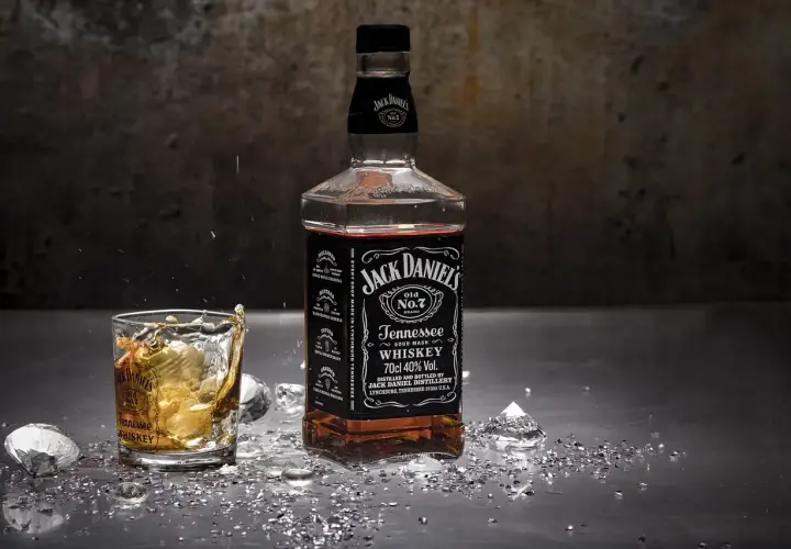 Burbon co to? Butelka Jack Daniel's Tennessee Whiskey i szklanka z drinkiem, lodem i rozbryzgami.