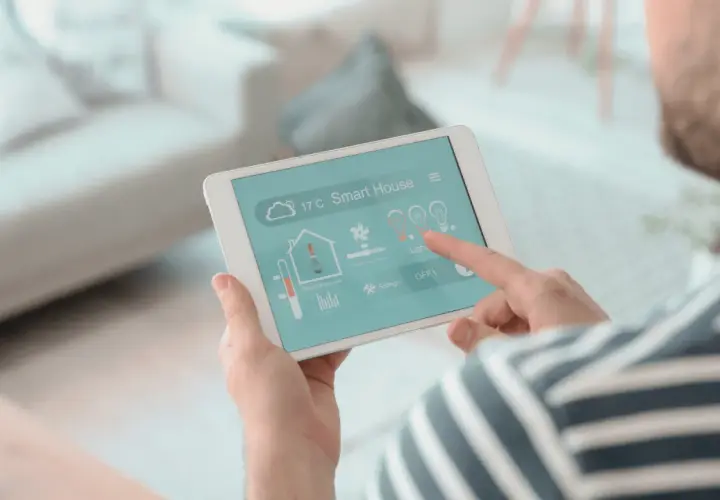 Un hombre controla su hogar inteligente desde una tablet, un vistazo a la historia de la domótica.