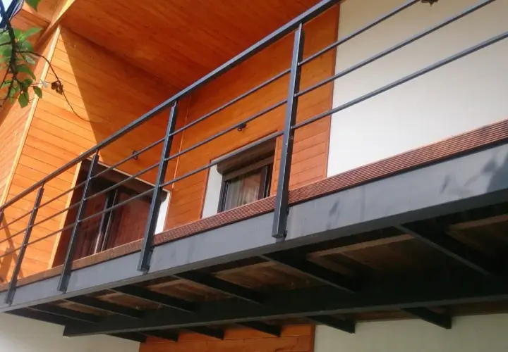 Nowoczesny balkon dostawny z metalową balustradą i drewnianą podłogą. Sprawdź, jaka balkon dostawny cena Cię czeka!