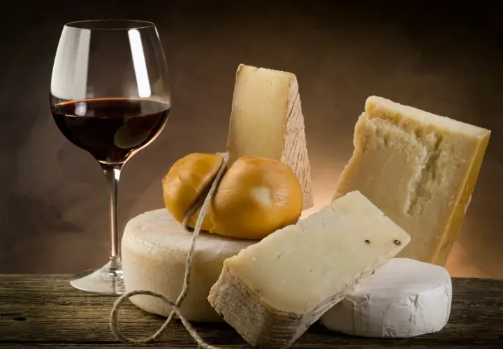 Un verre de vin rouge et une sélection de fromages, un accord parfait pour savoir quel vin avec le fromage.