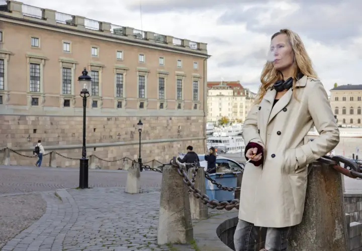 Sara Mac Key, med hörlurar runt halsen, tar en cigarettpaus vid vattnet i Stockholm.