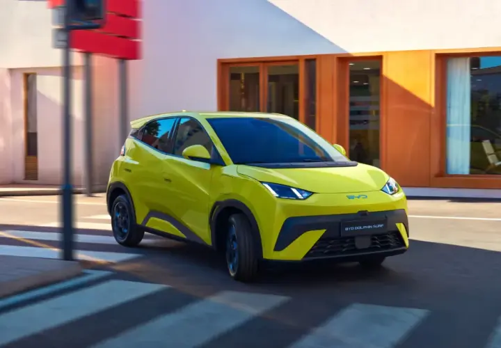 Żółty BYD Dolphin Surf sunie ulicą, niczym mewa nad wodą, w słoneczny dzień.