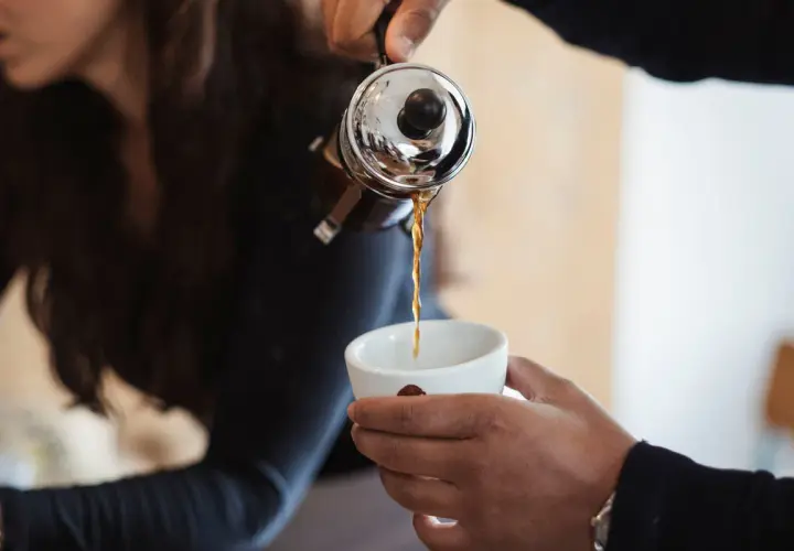 Eine French Press wird benutzt, um frisch gebrühten Filterkaffee in eine Tasse zu gießen.