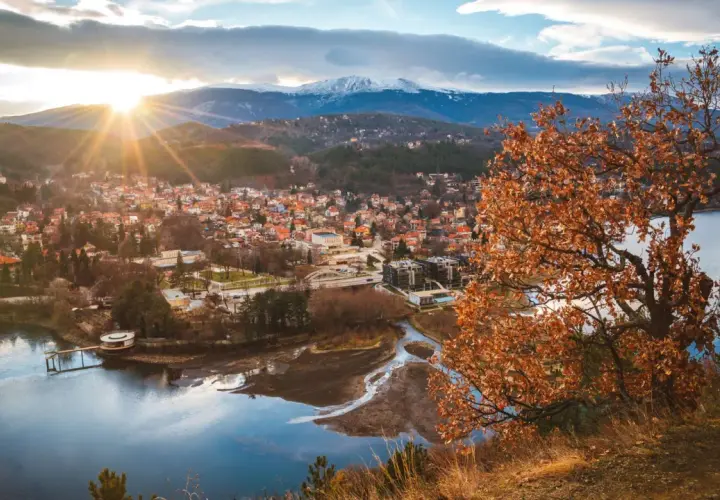 Widok na miasteczko nad jeziorem, góry w tle. Idealne miejsce, gdzie na wakacje w sierpniu, choć liście drzew już brązowe.