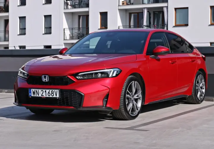 Czerwony Honda Civic Si na parkingu przed nowoczesnym budynkiem. Sportowy wygląd i dynamiczna linia nadwozia.