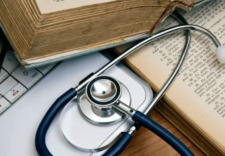 Libri antichi e uno stetoscopio su una tastiera, evocano lo studio della medicina legale.