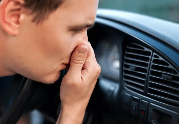 Man håller för näsan i bilen, en tydlig signal att det är dags att ta bort dålig lukt i bil.