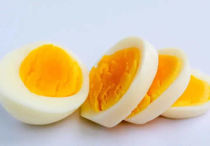 Ein halbes und drei Scheiben hartgekochtes Ei auf weißem Hintergrund. Ein Ei hat viel Protein.