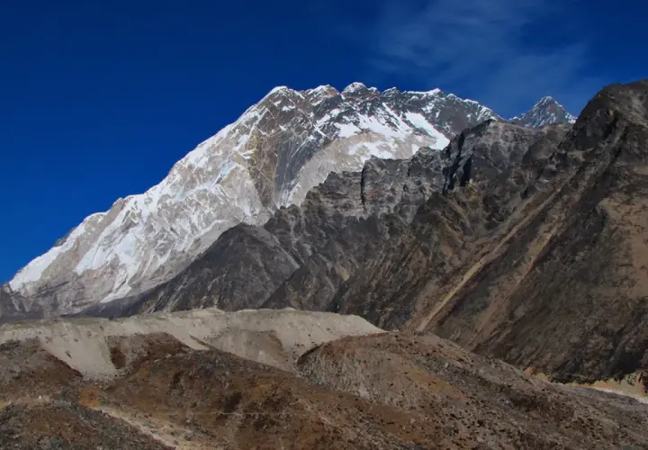 Majestatyczny Mount Everest w śnieżnej koronie, widok z bazy pod Everestem. Surowe, skaliste zbocza i błękitne niebo.