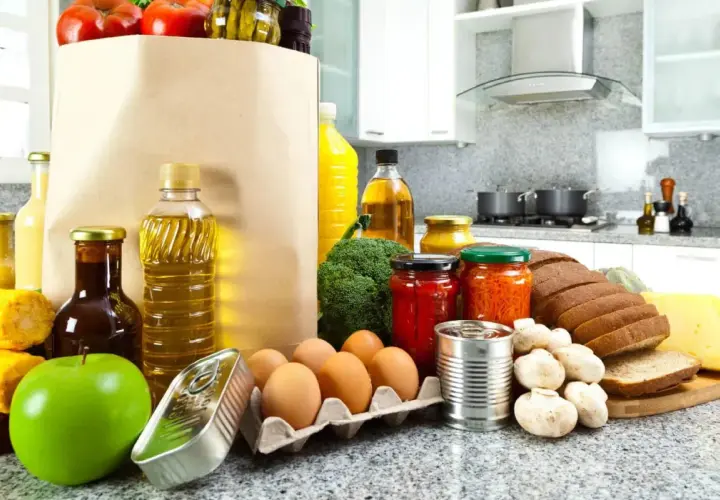 Un sacco di carta pieno di pomodori, uova, pane, formaggio e altri cibi proteici, pronti per essere cucinati.