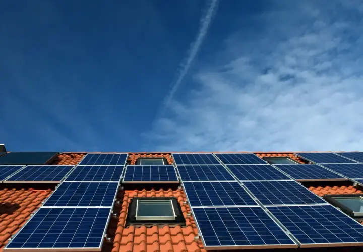 Nowoczesna instalacja PV na dachu z dachówką, pod błękitnym niebem. Panele słoneczne zbierają energię.