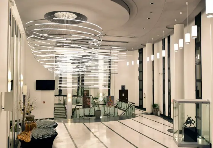 Nowoczesny, przestronny foyer z imponującą, wielopoziomową lampą i szklaną gablotą z rzeźbą.