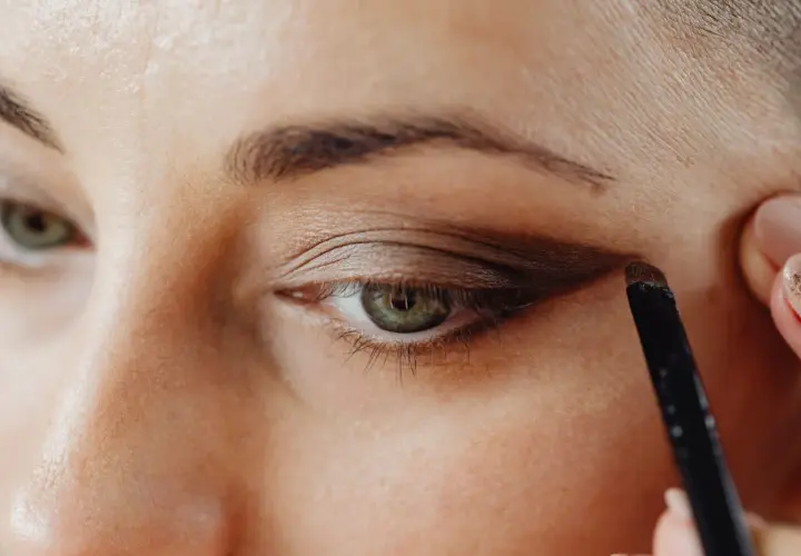Application d'un fard brun pour comment maquiller des yeux verts. Un pinceau est utilisé pour définir la paupière.