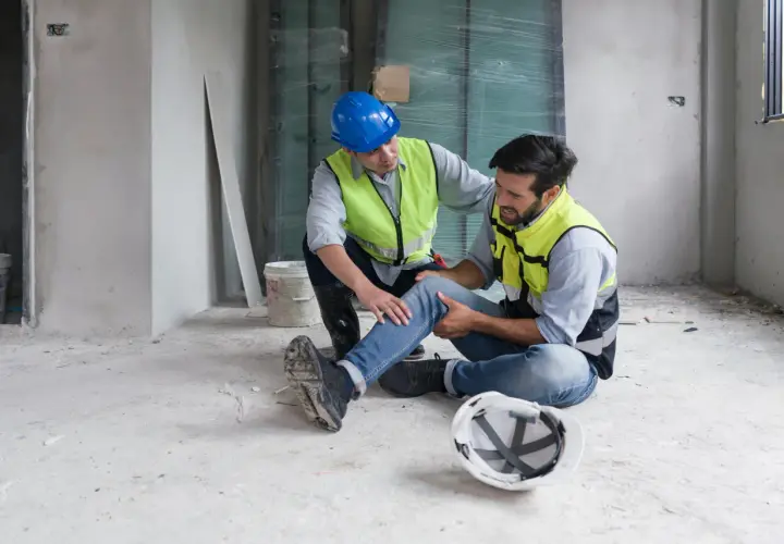 Operaio ferito assistito da un collega. La scena evoca la necessità di un risarcimento per morte sul lavoro o infortunio grave.