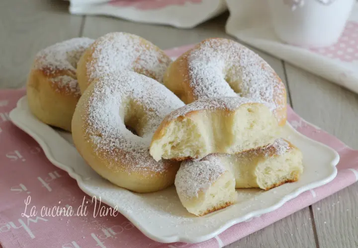 Ciambelle al forno soffici e profumate, cosparse di zucchero a velo. Una delizia per la colazione o la merenda.
