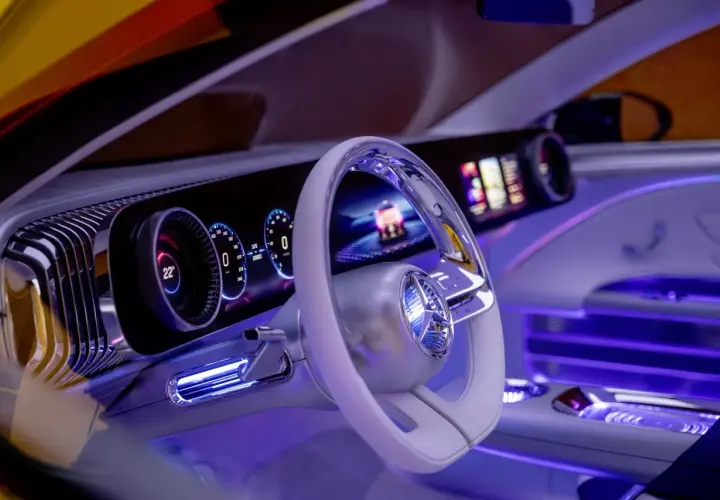 Wnętrze Mercedesa CLA z futurystycznym kokpitem, podświetlanym na niebiesko. Widoczny ekran, kierownica i cyfrowe zegary.