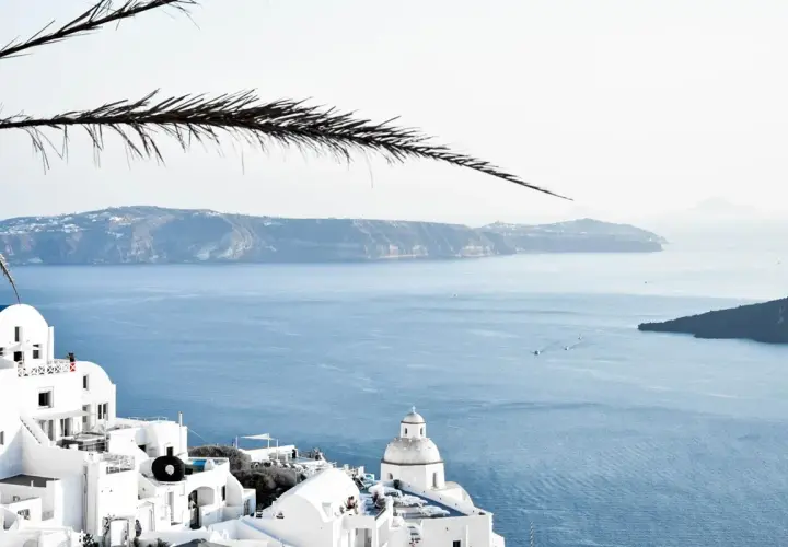 Santorini, Grecja. Białe domy na klifie, błękitne morze i wyspy w oddali. Ciekawe miejsca i widoki.