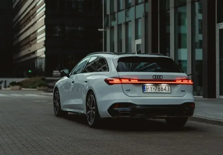 Białe Audi A5 Avant 2025 z nowoczesnymi światłami LED na tle miejskiej architektury.