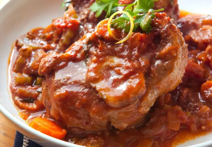 Herzhaftes Ossobuco Rezept in Tomatensoße mit Karotten und Petersilie, serviert in einer weißen Schüssel.