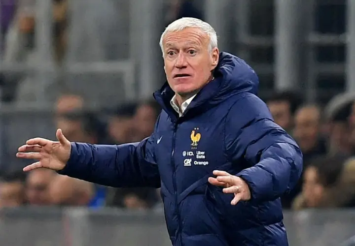 Didier Deschamps, trener Francji, w niebieskiej kurtce z herbem reprezentacji, gestykuluje na boisku.