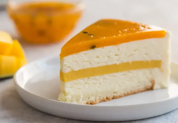 Pyszny kawałek tortu z warstwami białego kremu i żółtym musem mango, zwieńczony galaretką z mango.